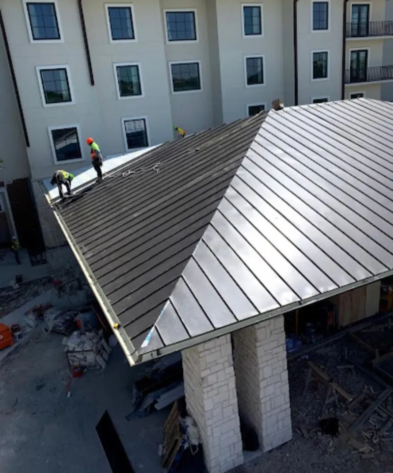 Crew installing standing seam metal roof panels on a commercial project in Cortland